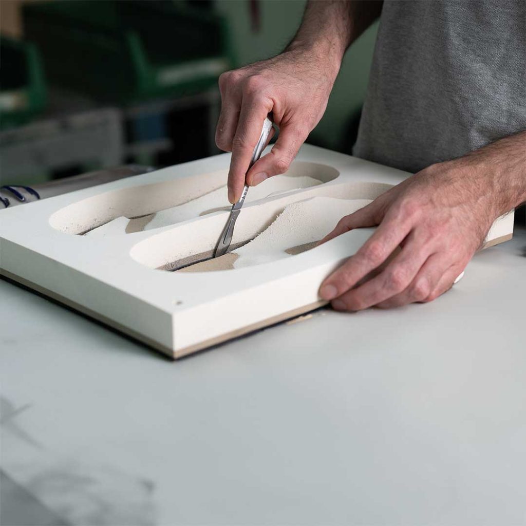 Mani di un tecnico rifiniscono un blocco di EVA appena preso dalla fresa